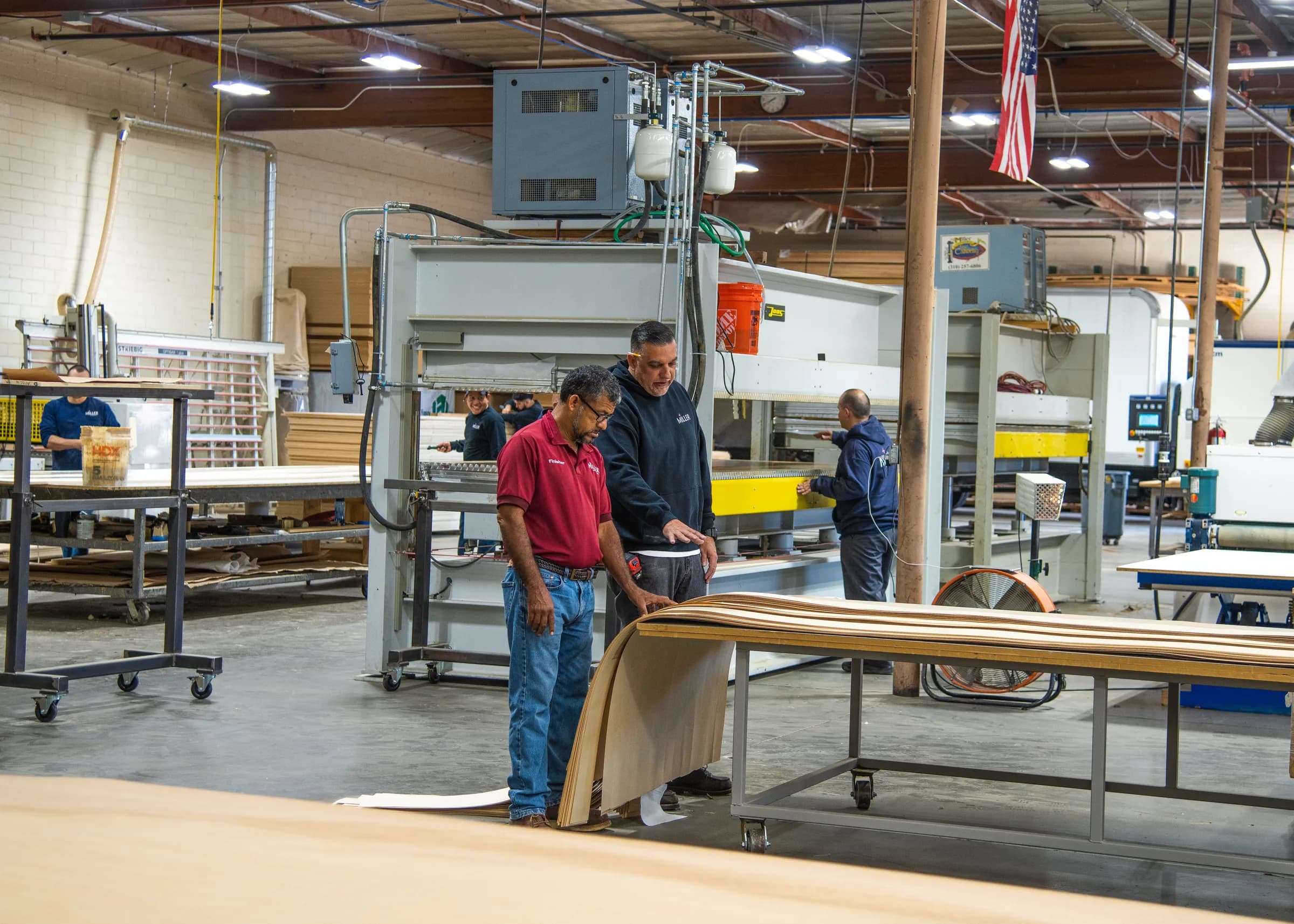 Three shop hands at the bench with a flitch of leaves, the press behind them.